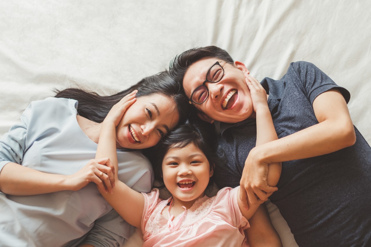 A family laughing on a bed