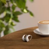 Hearing aids on a table next to a cappuccino cup