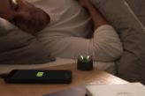 A senior man sleeping with his hearing aids charging in a charger beside him