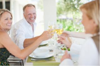 Varias personas haciendo un brindis mientras comen juntos sentados alrededor de una mesa