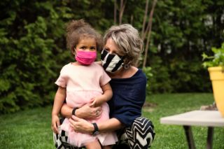 A grandmother holding her granddaughter in her arms in a garden