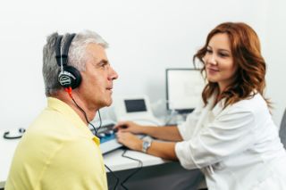 A man taking a hearing screening with an Amplifon hearing professional
