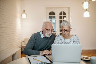 A senior couple looking for information on their home laptop